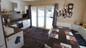 Cocina moderna con comedor, pisos de madera y vista a un paisaje nevado.