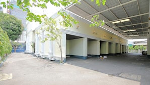 An empty building with a covered parking area, columns, and a tree in the foreground. - OYO 1002 Pinklao Resort (Bangkok)
