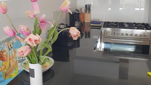 Eine moderne Küche mit einem Gasherd, Backofen und einer Vase mit rosa Tulpen auf der Arbeitsfläche.