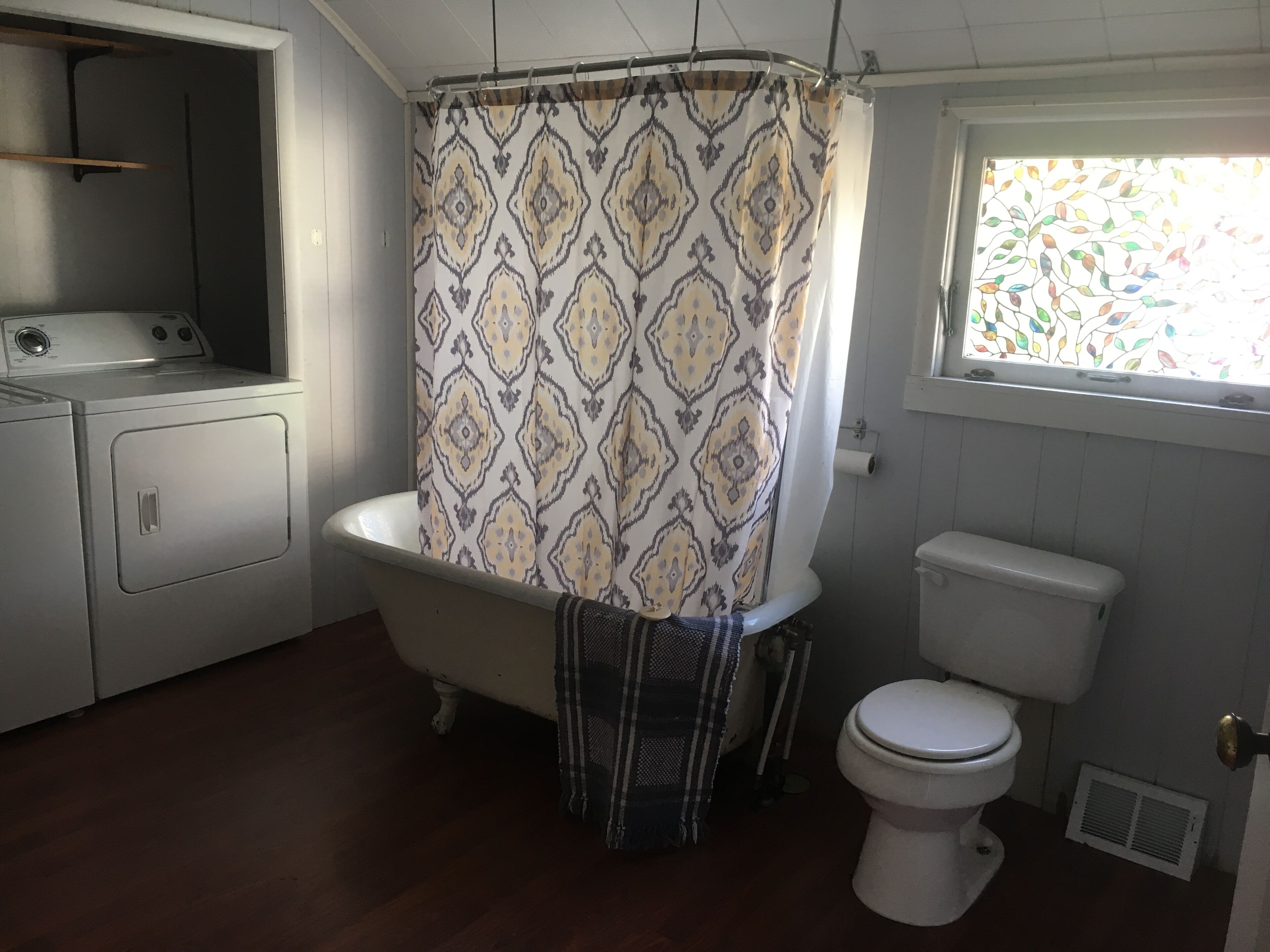A bathroom with a bathtub, toilet, and washing machine.