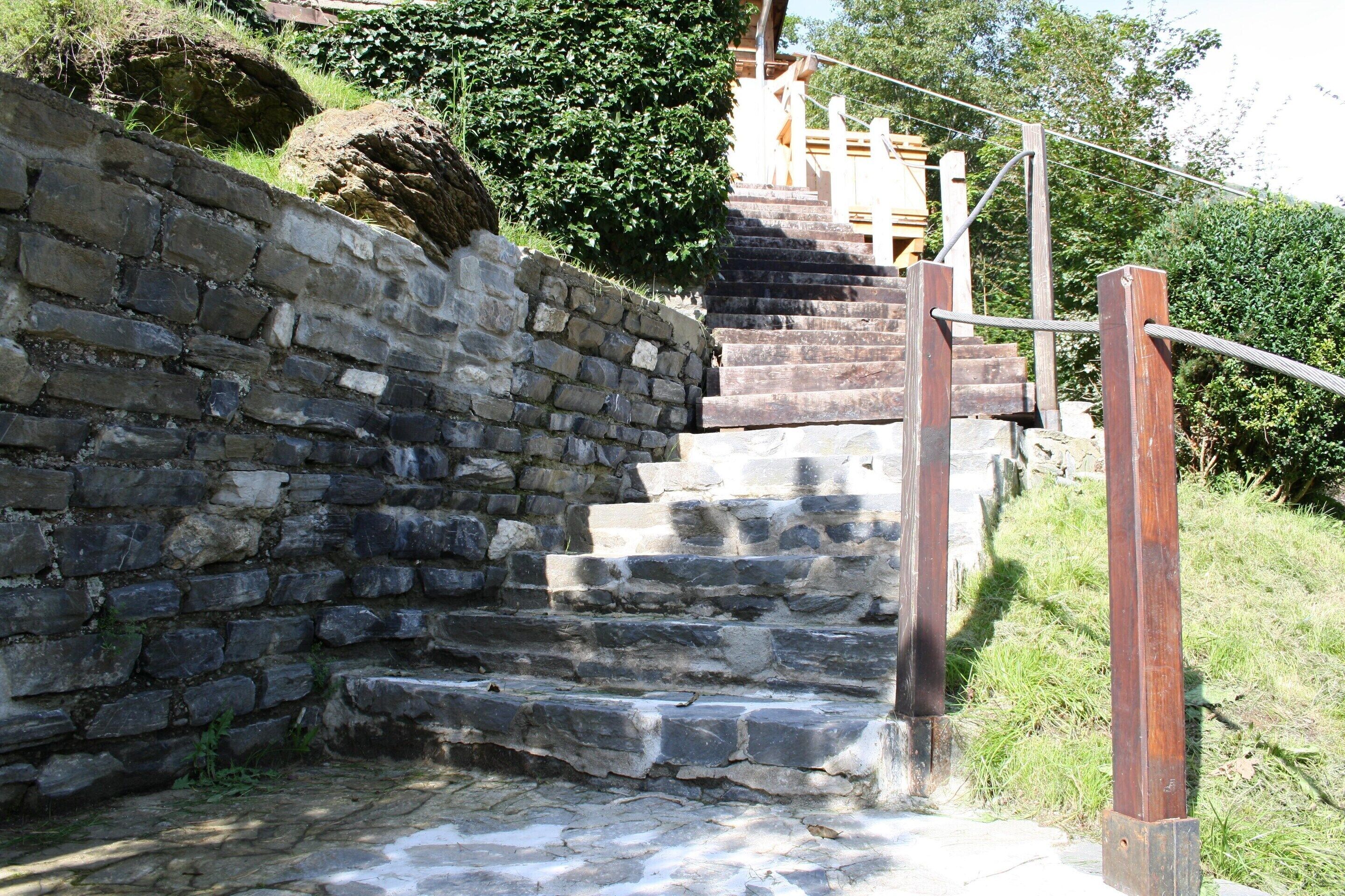 A stone staircase leading up to a wooden structure with metal railings.