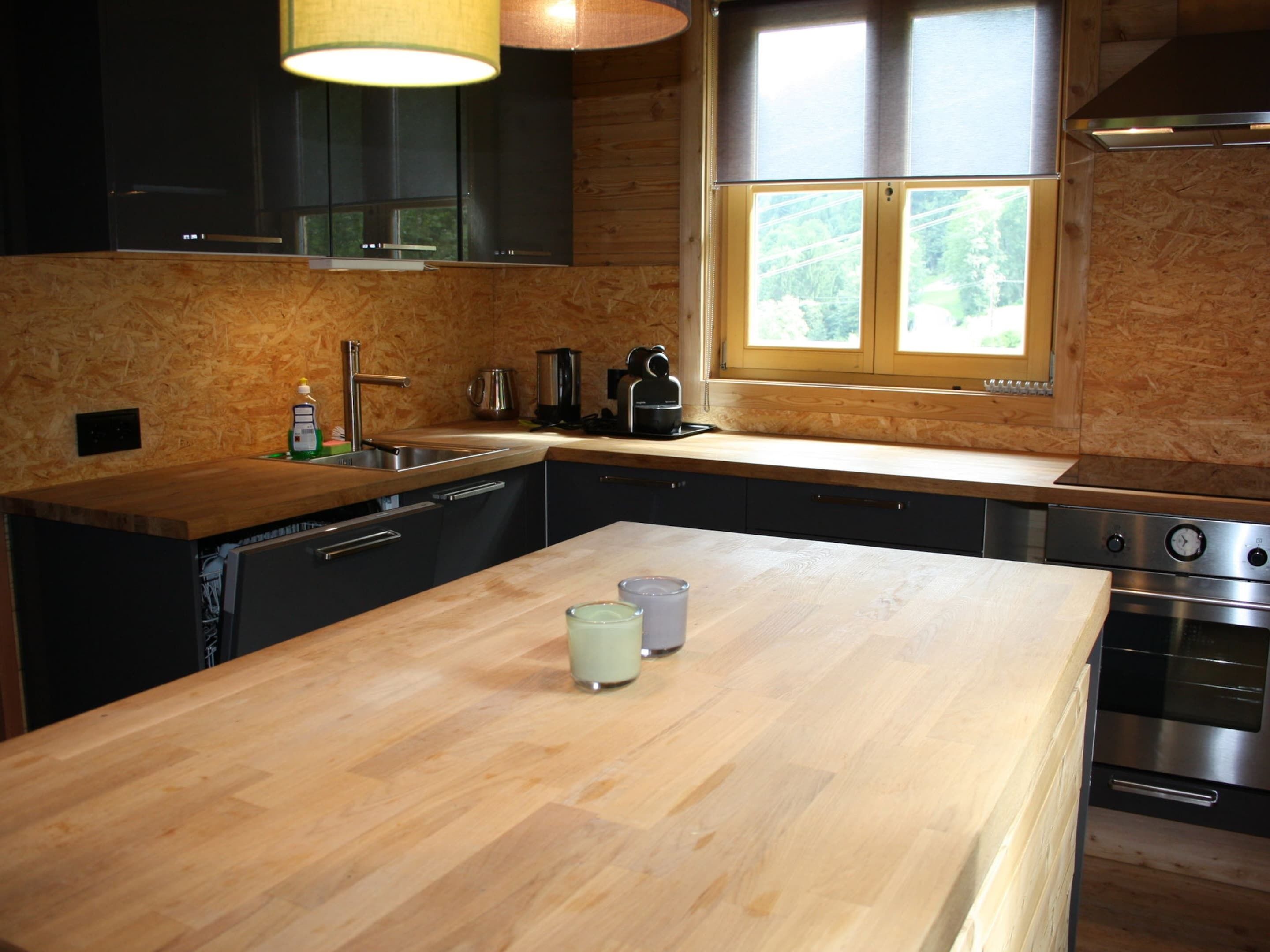 Una cocina moderna con encimera de madera, electrodomésticos de acero inoxidable y un ventanal que proporciona luz natural.
