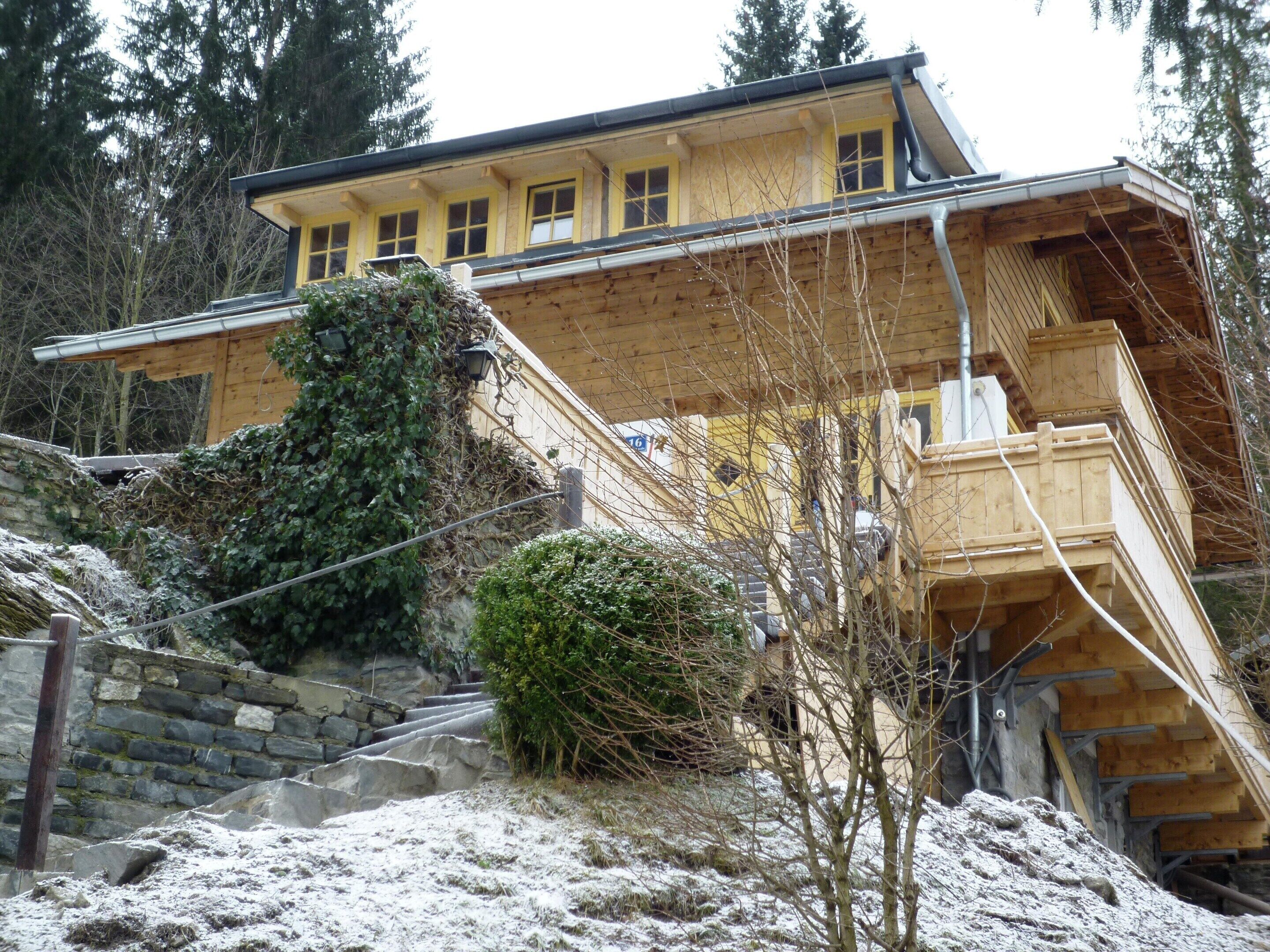 A multi-story wooden building with a stone staircase leading up to a wooden deck.