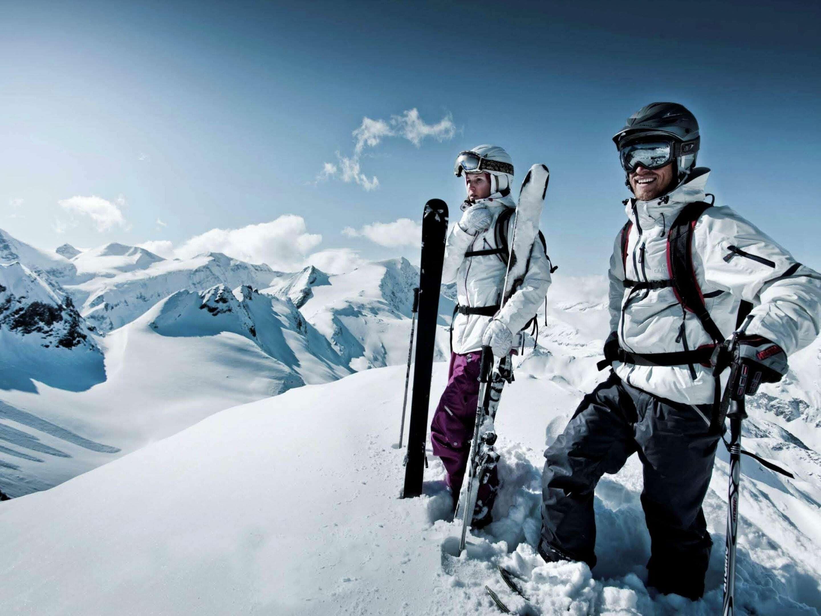 Two skiers on a snowy mountain with a clear sky.