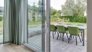 Une chambre moderne dotée d’une porte-fenêtre coulissante donnant sur un patio extérieur avec une table et des chaises.