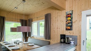 Ein Holzinterieur mit einem für vier Personen gedeckten Esstisch, einer Kaffeemaschine und einem an der Wand befestigten Gewürzregal.