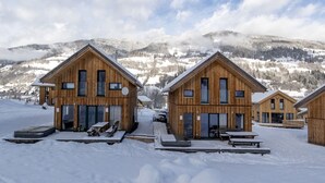 Eine Holzhütte mit einer großen Veranda und Blick auf schneebedeckte Berge.