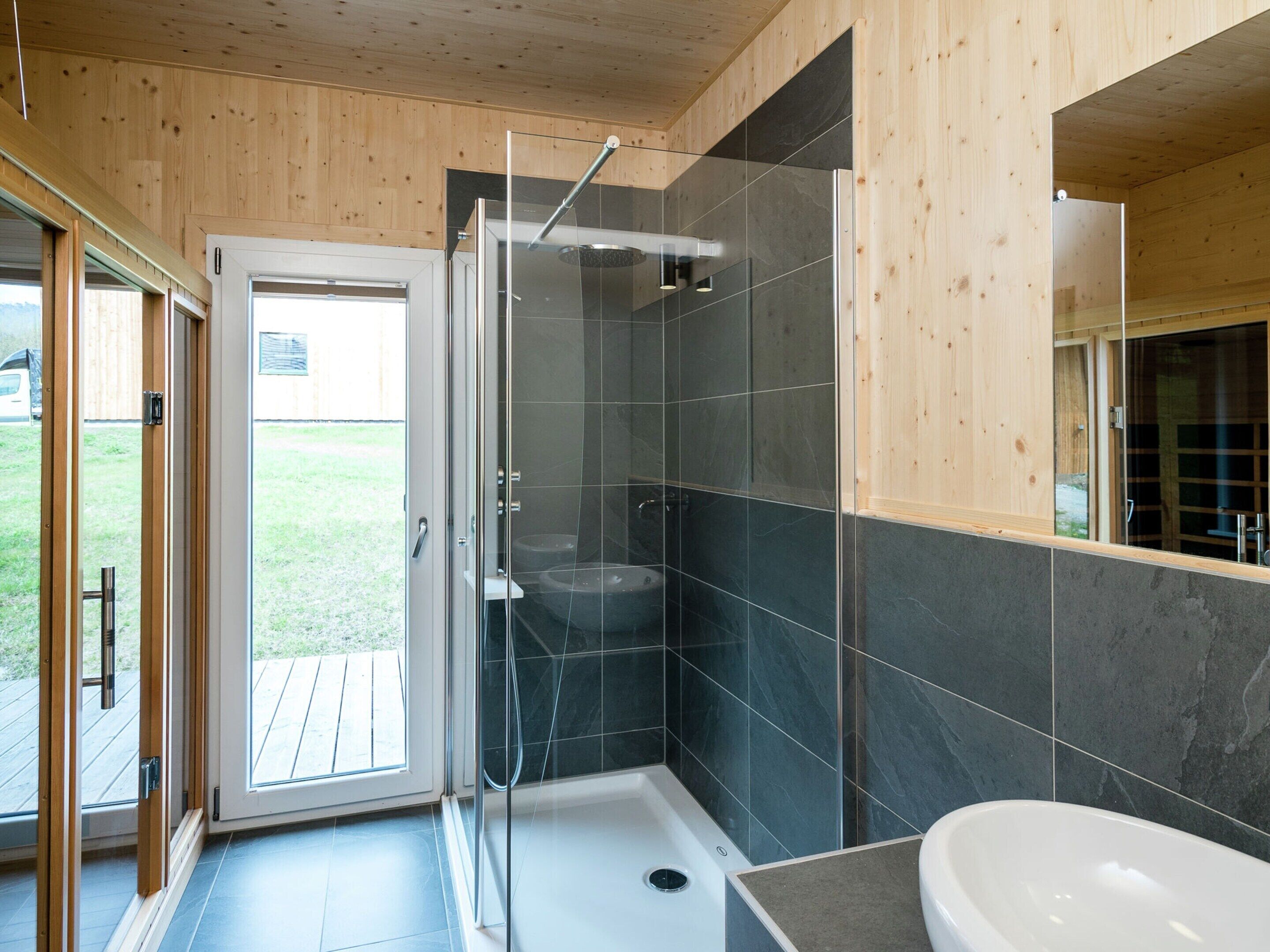A modern bathroom with a glass shower enclosure, a bathtub, and a large mirror.