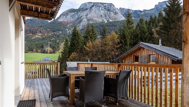 A wooden deck with a table and chairs, overlooking a mountainous landscape. - Chalet in Dachstein West With Shared Pool (Annaberg-Lungoetz)