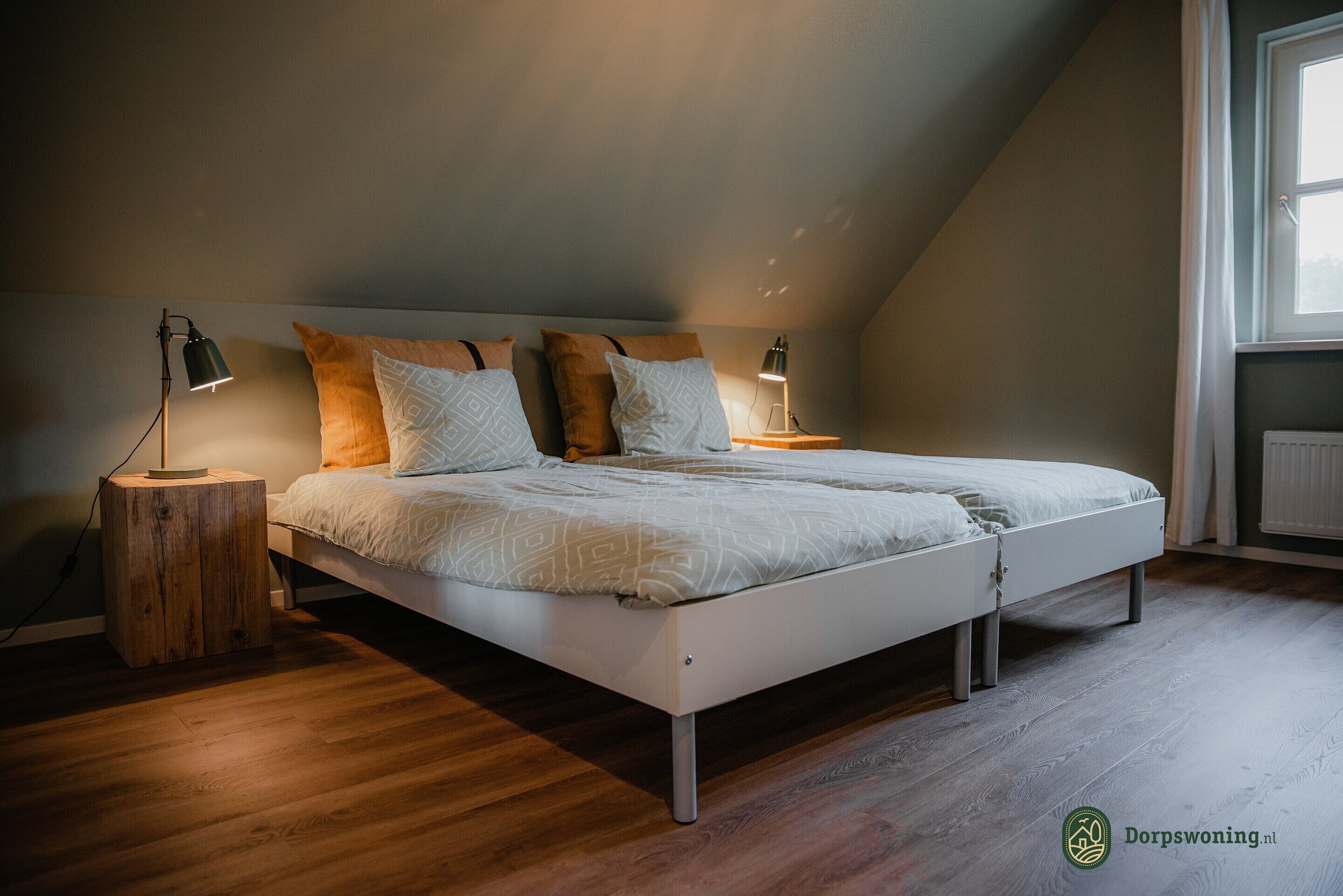 A modern bedroom with a white bed, wooden flooring, and two bedside lamps.