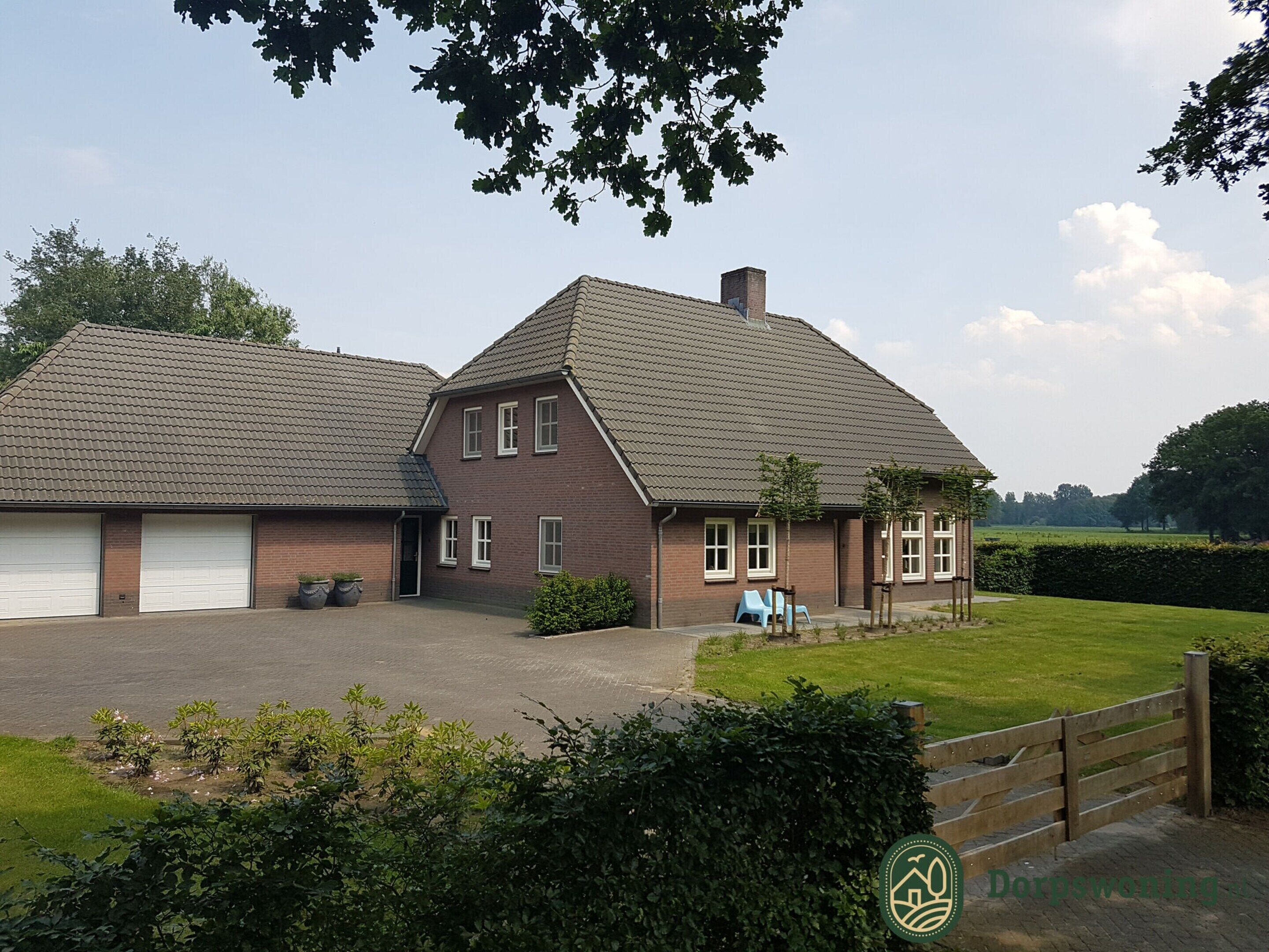 Ein zweistöckiges Haus mit Garage, überdachter Veranda und gepflegtem Rasen.