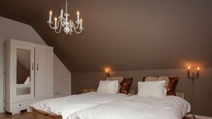 A bedroom with a large bed, wooden headboard, a wardrobe, and a chandelier.