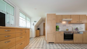 Eine moderne Küche mit Holzausstattung, Fliesenboden und einem eingebauten Ofen.