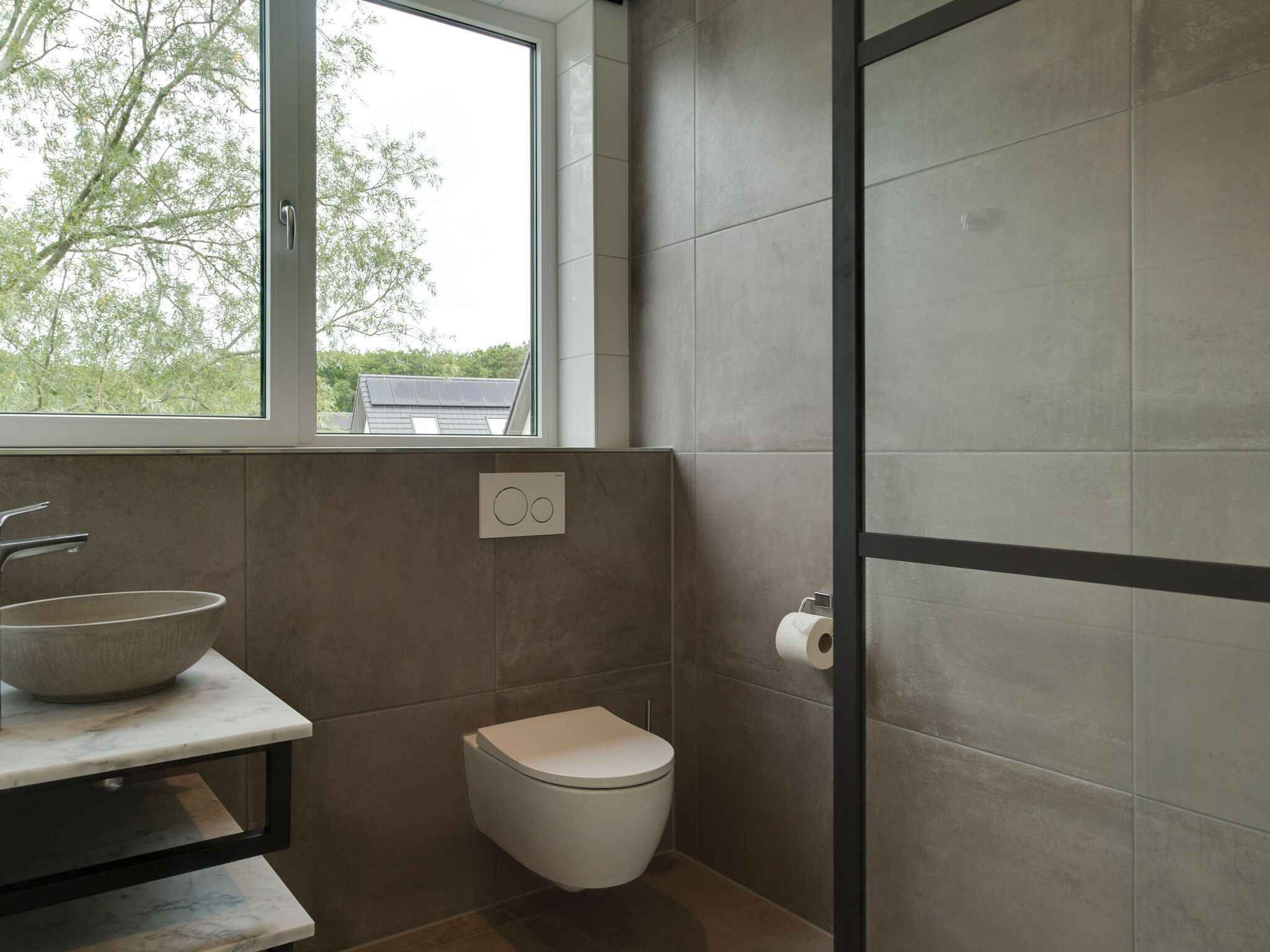 Et moderne badeværelse med et stort vindue, en vask og et toilet.