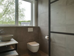 A modern bathroom with a large window, a sink, and a toilet. - Bungalow in Texel Near National Park (De Koog)