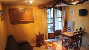 Ein Essbereich mit Schachbrettmuster-Boden, Holzmöbeln, einem kleinen Tisch mit Pizza und einem Fenster mit Vorhängen.