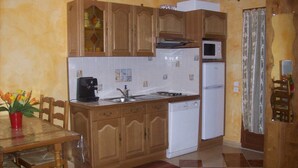 Eine kleine Küche mit Holzausstattung, einer Kaffeemaschine, einer Mikrowelle und einem Kühlschrank.