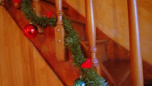 Eine Holztreppe mit einer Girlande aus Grünpflanzen und roten Verzierungen.