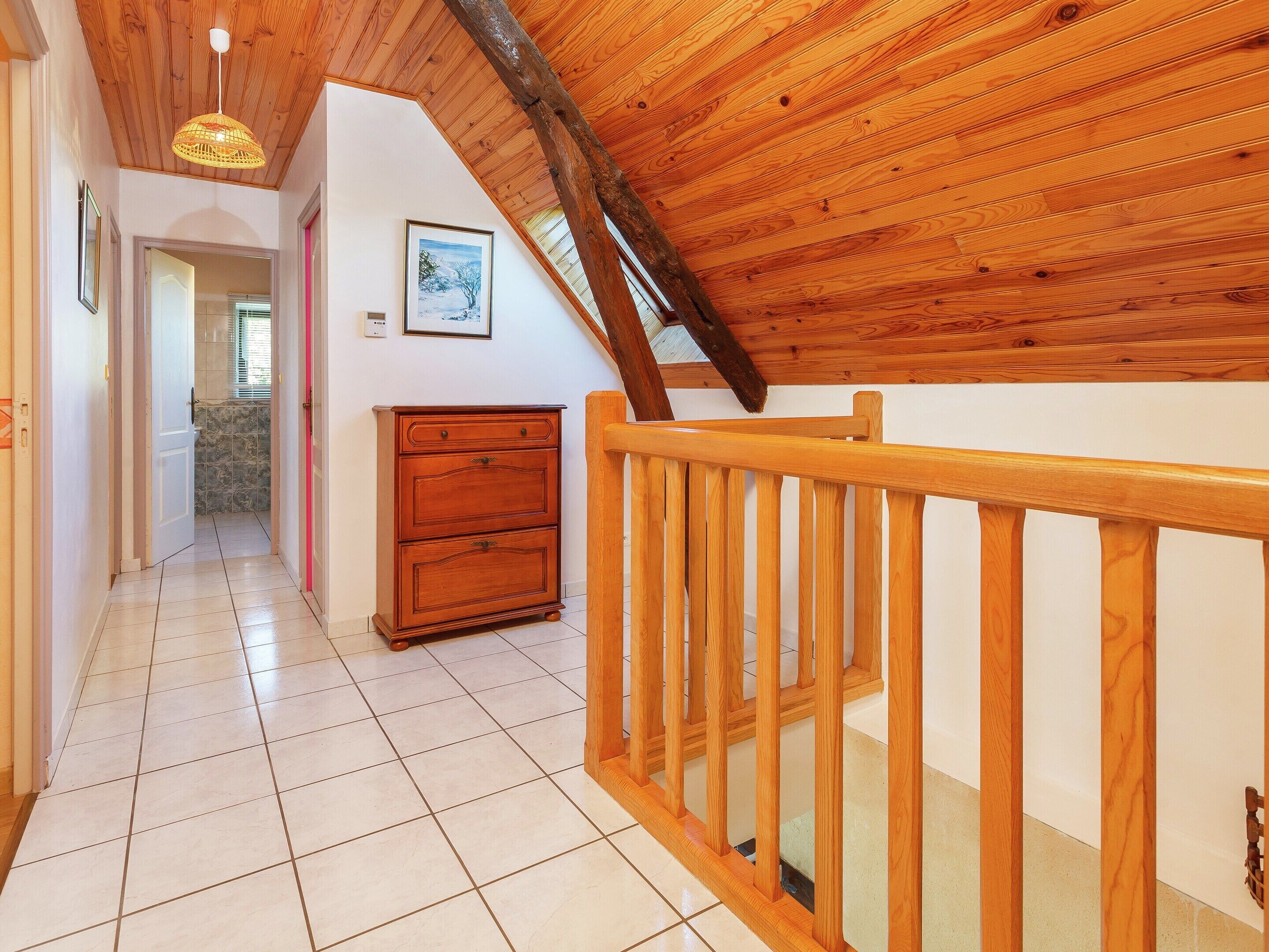 Un corridoio con pavimento e ringhiera in legno, e una scala dotata di una balaustra in legno.