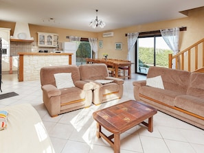 A living room with a sofa set, a coffee table, and a dining area with a table and chairs. - Cosy Holiday Home Near the Causses du Quercy (Lavercantiere)