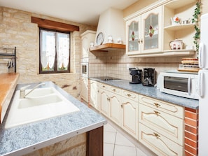 A kitchen with a stone wall, a sink, cabinets, a microwave, and a coffee maker. - Cosy Holiday Home Near the Causses du Quercy (Lavercantiere)
