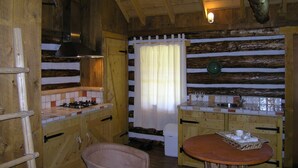 A rustic kitchen with wooden walls, a gas stove, a sink, and a dining table with a basket of cups. - Holiday Home With Garden in Den Ham (Den Ham)