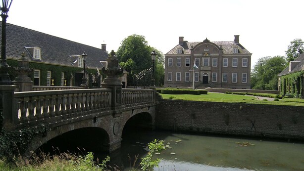 A stone bridge over a canal with a large building in the background. - Holiday Home With Garden in Den Ham (Den Ham)