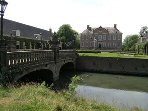 Eine Steinbrücke über einen Kanal, im Hintergrund ein großes Gebäude.