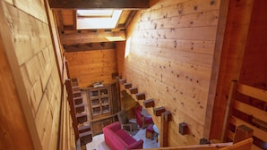 Een houten interieur met een trap, een rode bank en een kast met glazen deuren.