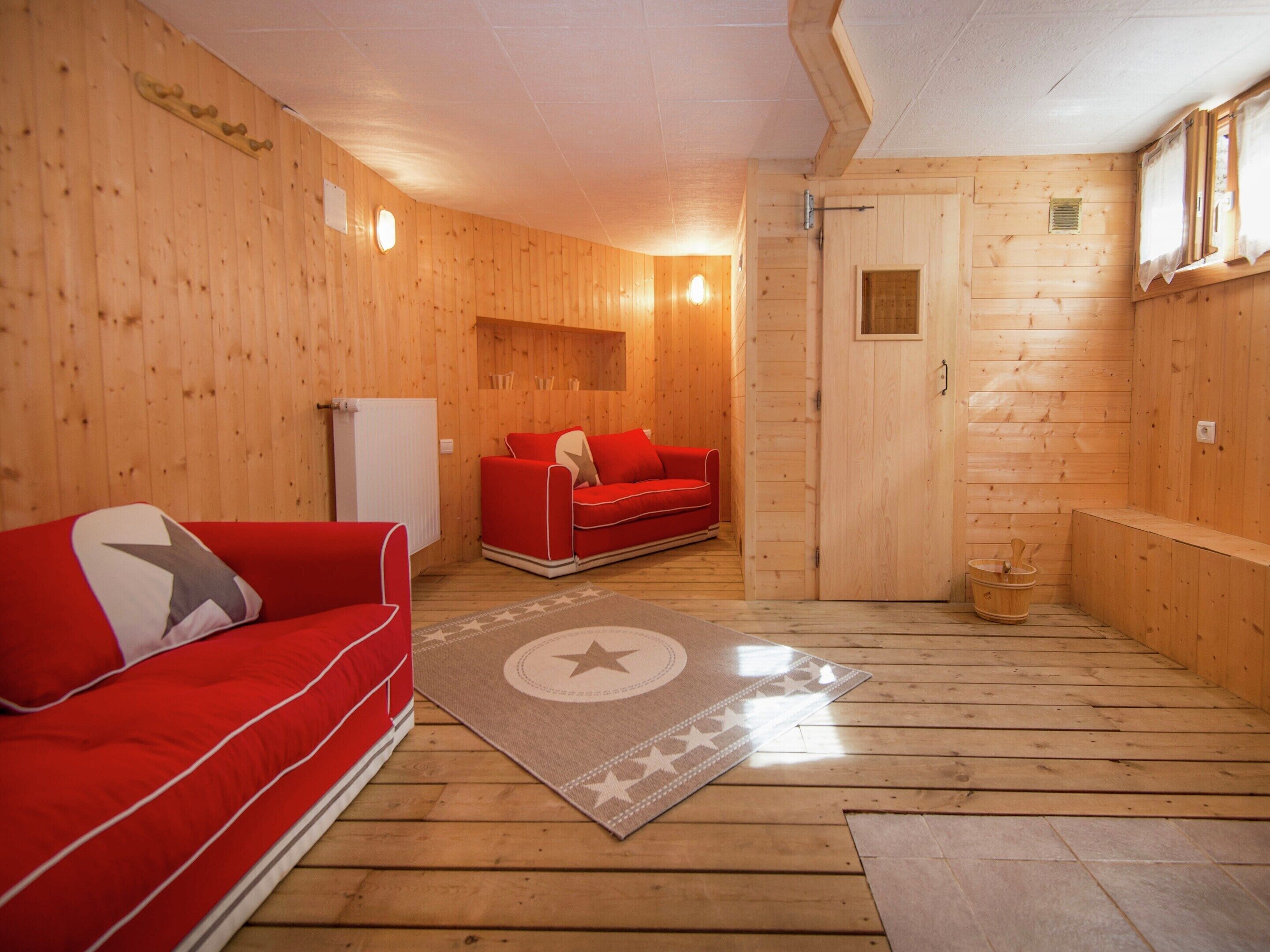 Un interno in legno con un divano rosso, una panca di legno e un piccolo tavolo con una ciotola.