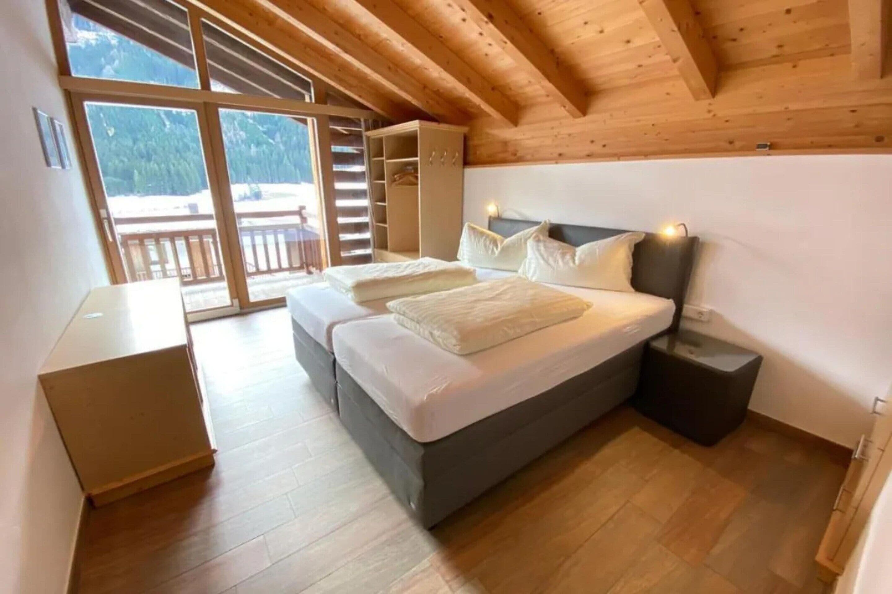 Un dormitorio con cama, mesitas de noche, armario y vistas a un balcón.