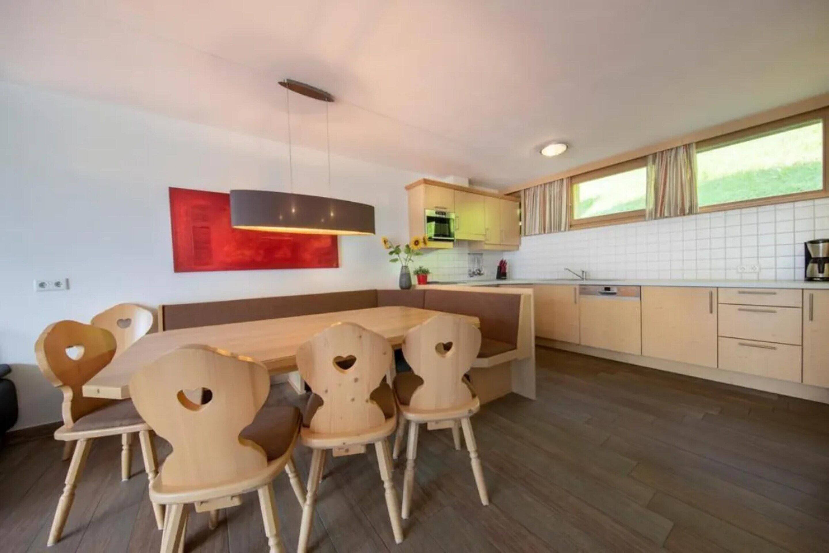 Et moderne køkken med træskabe, en central ø og hjerteformede stole.