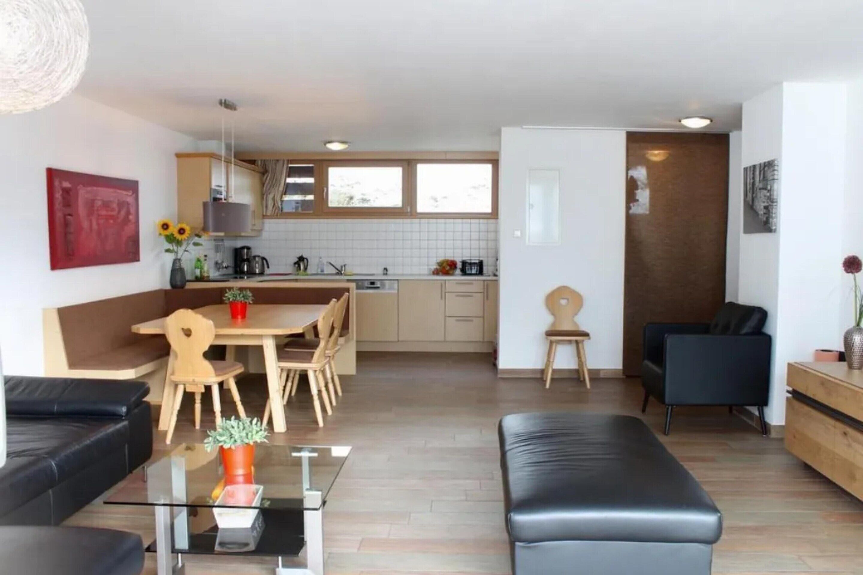 Ein modernes Wohnzimmer mit einer Couch, einem Glastisch und einem Essbereich mit Tisch und Stühlen.