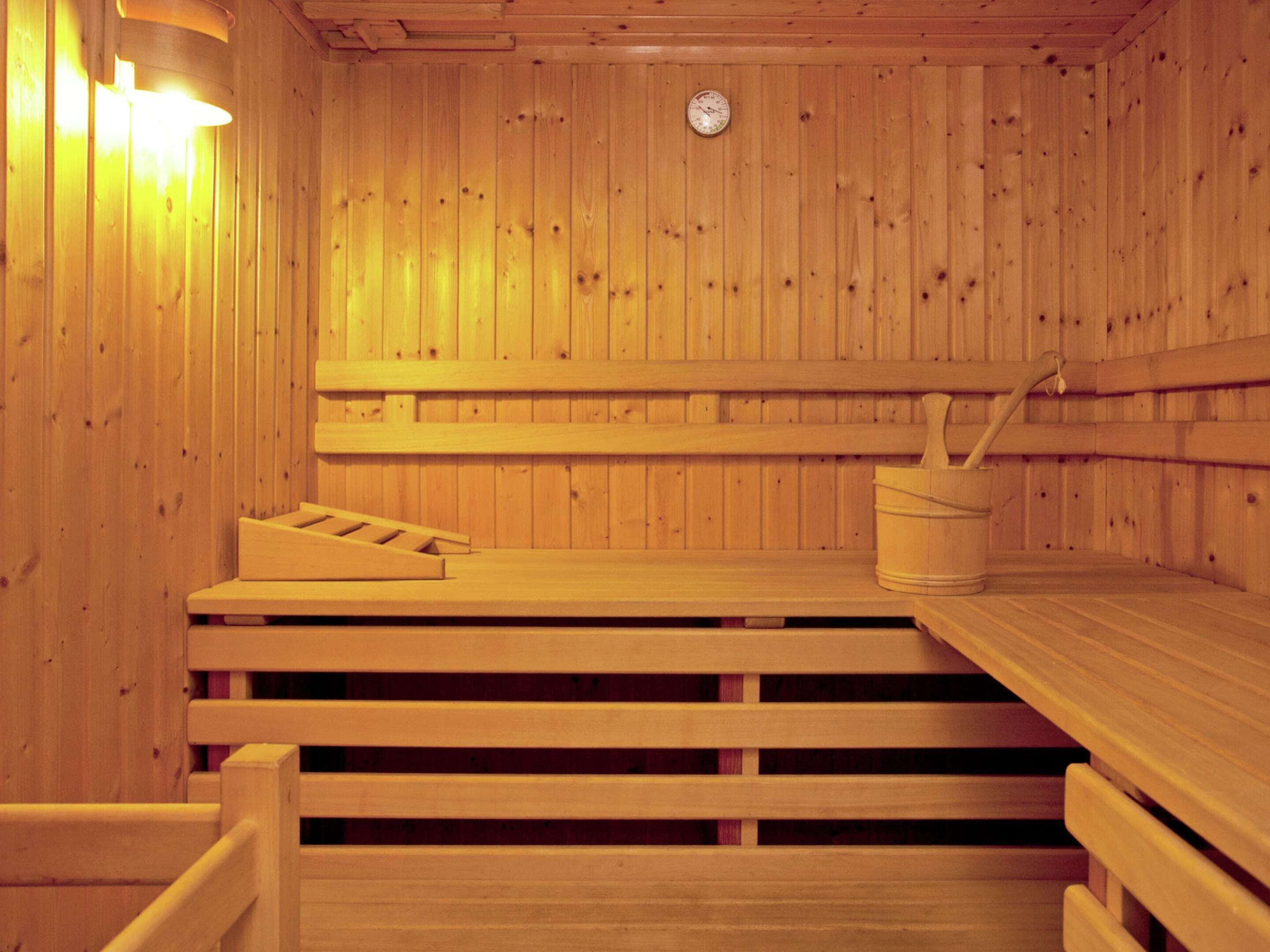 A wooden sauna with benches and a bucket.
