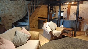 Ein rustikales Interieur mit Steinwand, Holztreppe und einer Küchenzeile.