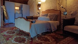 Ein Schlafzimmer mit einem hölzernen Bett, einem Nachttisch, einer Lampe, einer Kommode und einem Spiegel.