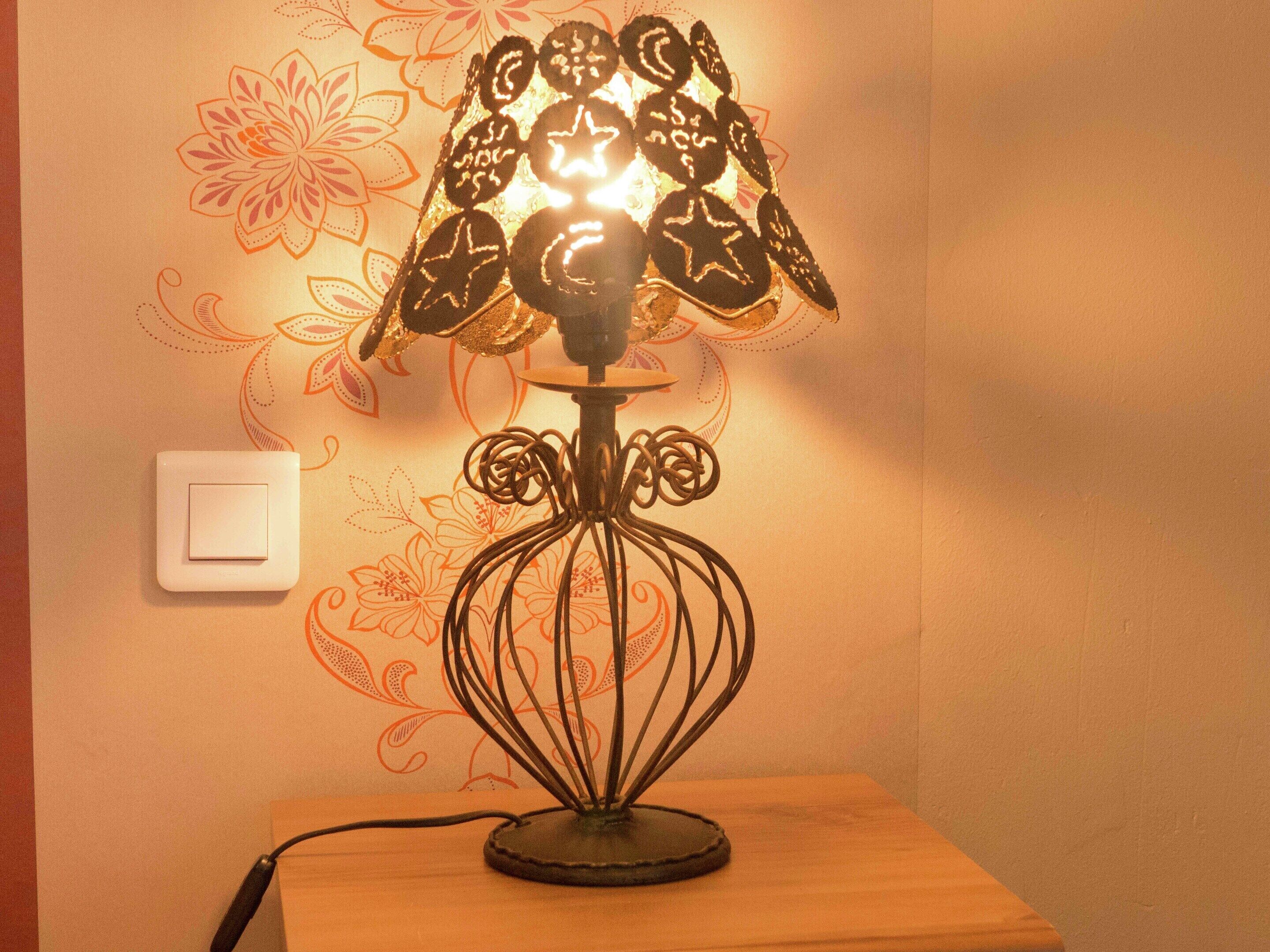 A table lamp with a decorative shade on a wooden table.