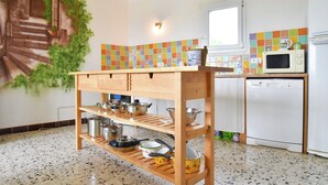 A kitchen with a wooden shelf unit, a microwave, a refrigerator, and a colorful backsplash. - Holiday Home Talairan With Pool and BBQ (Talairan)