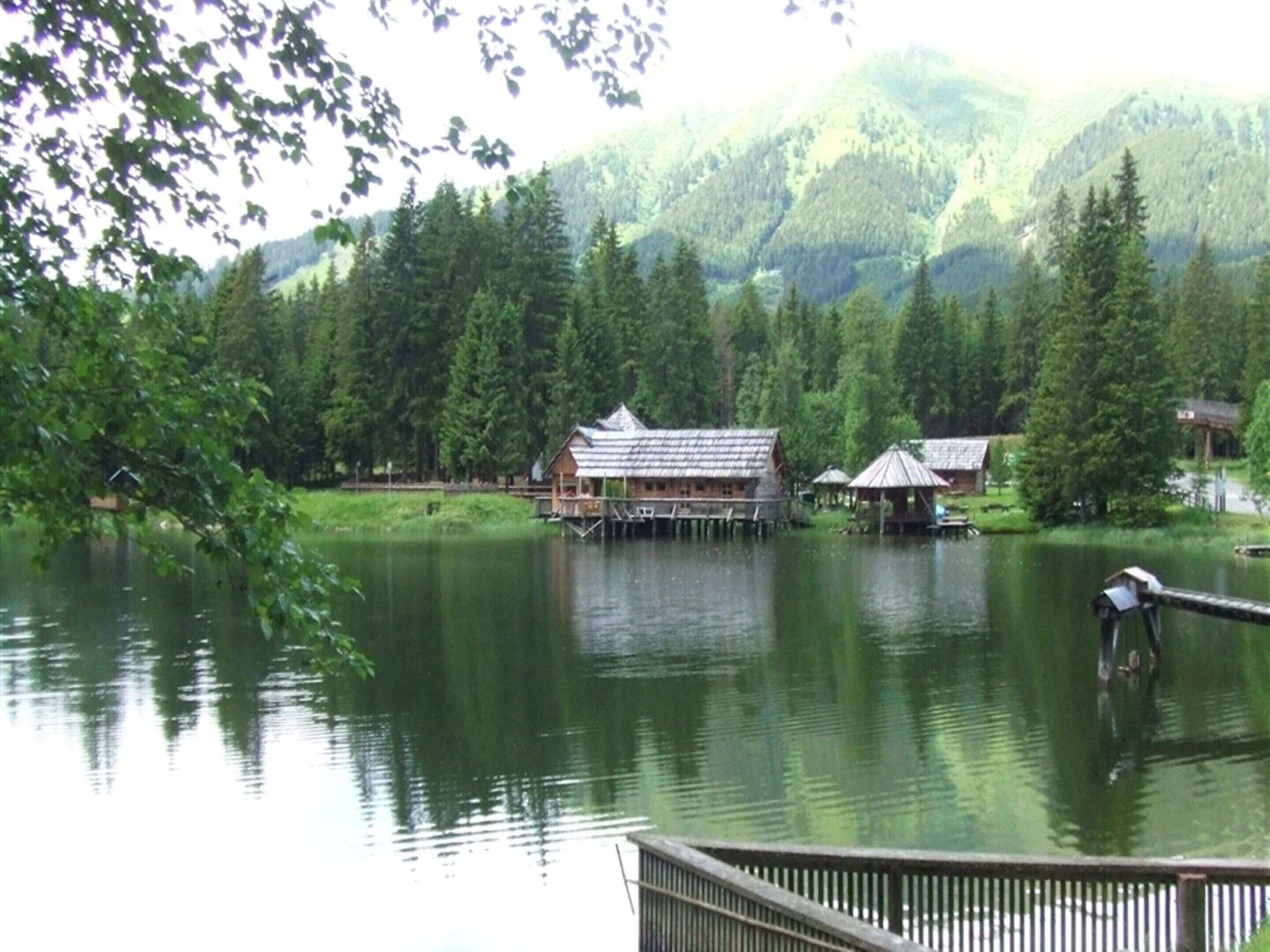 Una cabaña sobre pilotes en un lago rodeado de bosque.