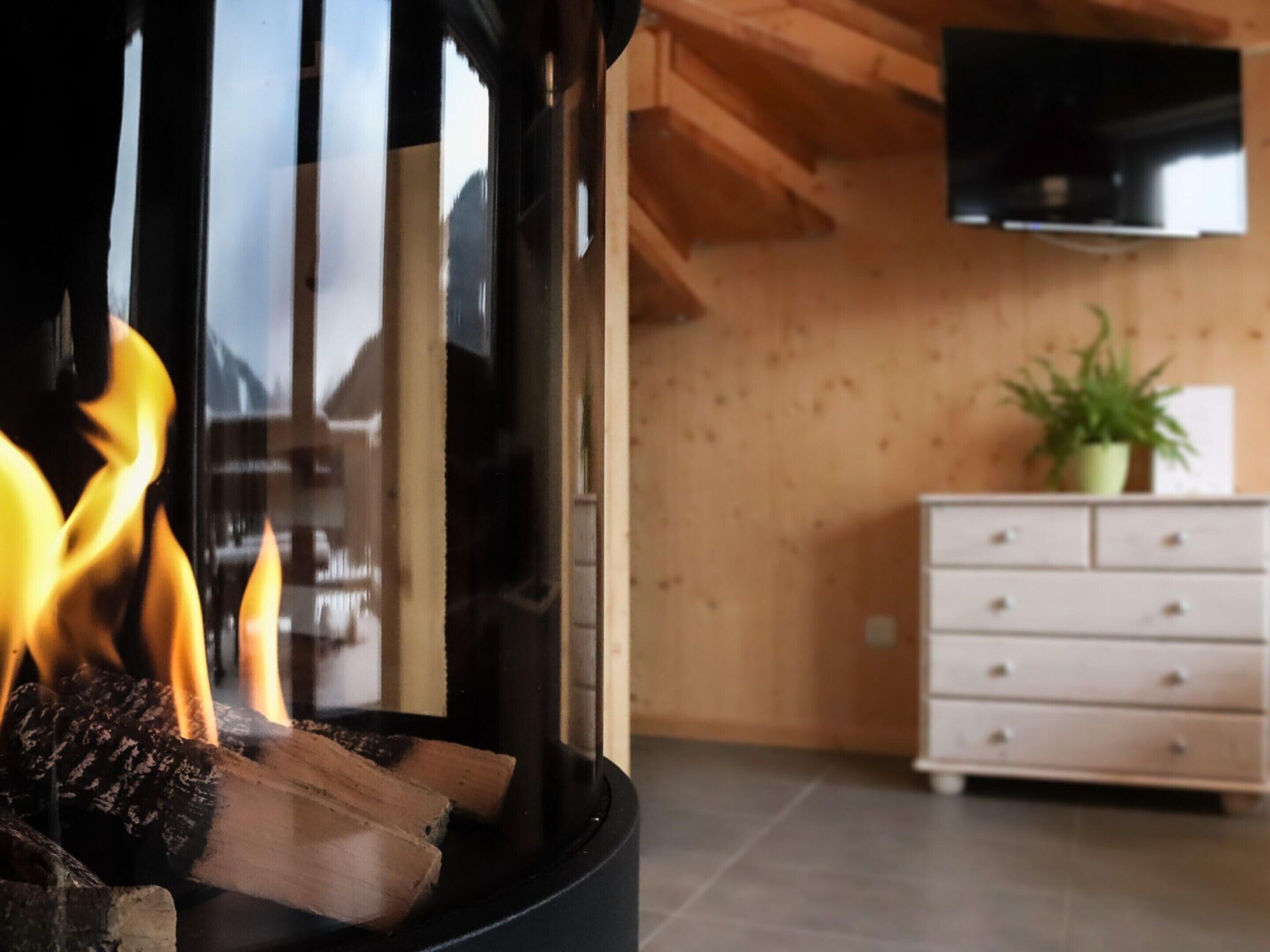 Una habitación con chimenea, paredes de madera, un tocador blanco y un televisor de pantalla plana montado en la pared.