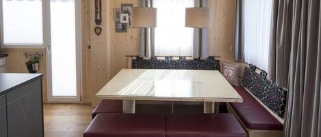 A cozy cabin interior with a wooden dining table, bench seating, and a built-in bench along the window.
