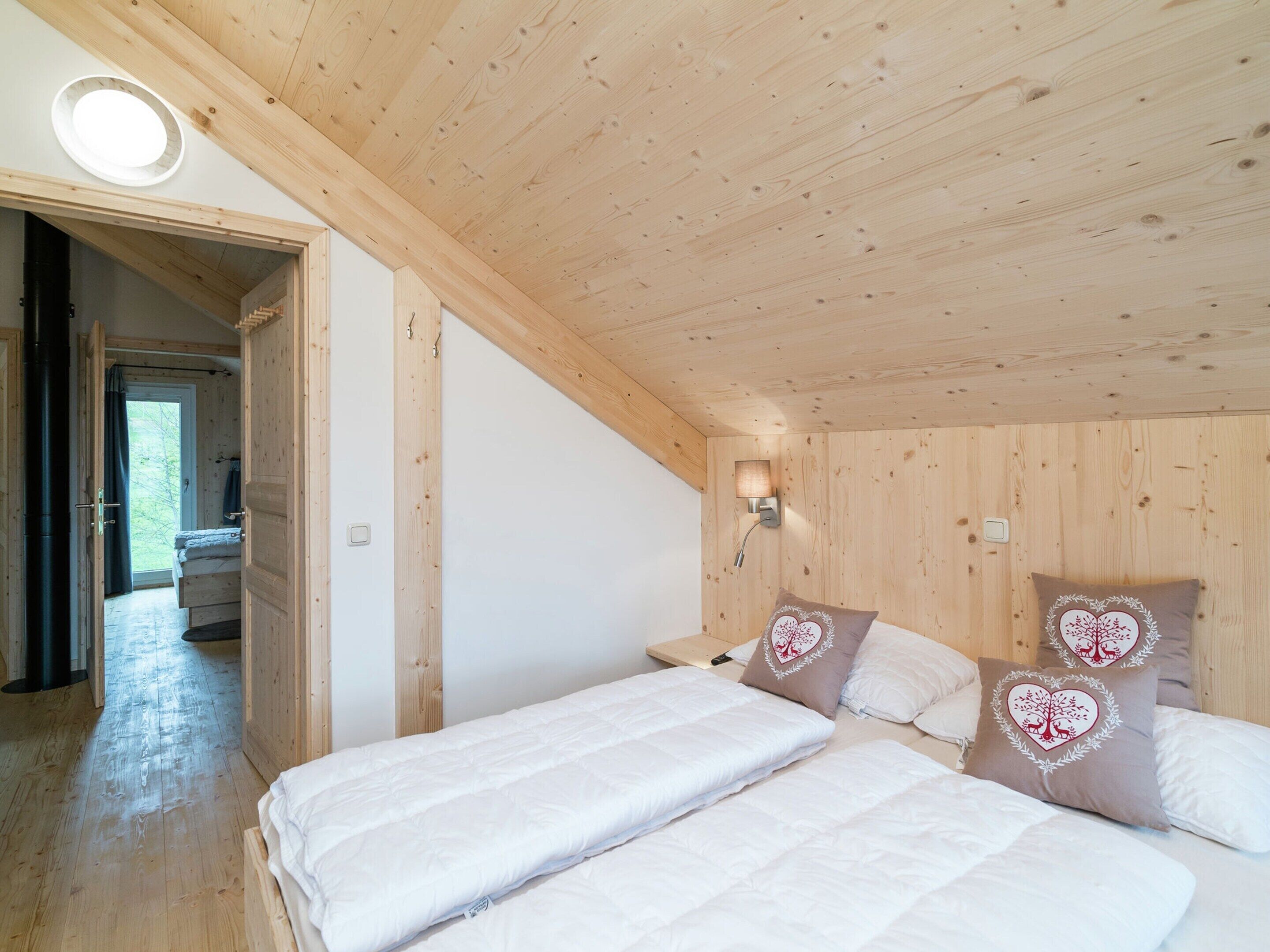 Une chambre avec des murs et un plafond en bois, un lit avec une literie blanche et un luminaire fixé au mur.