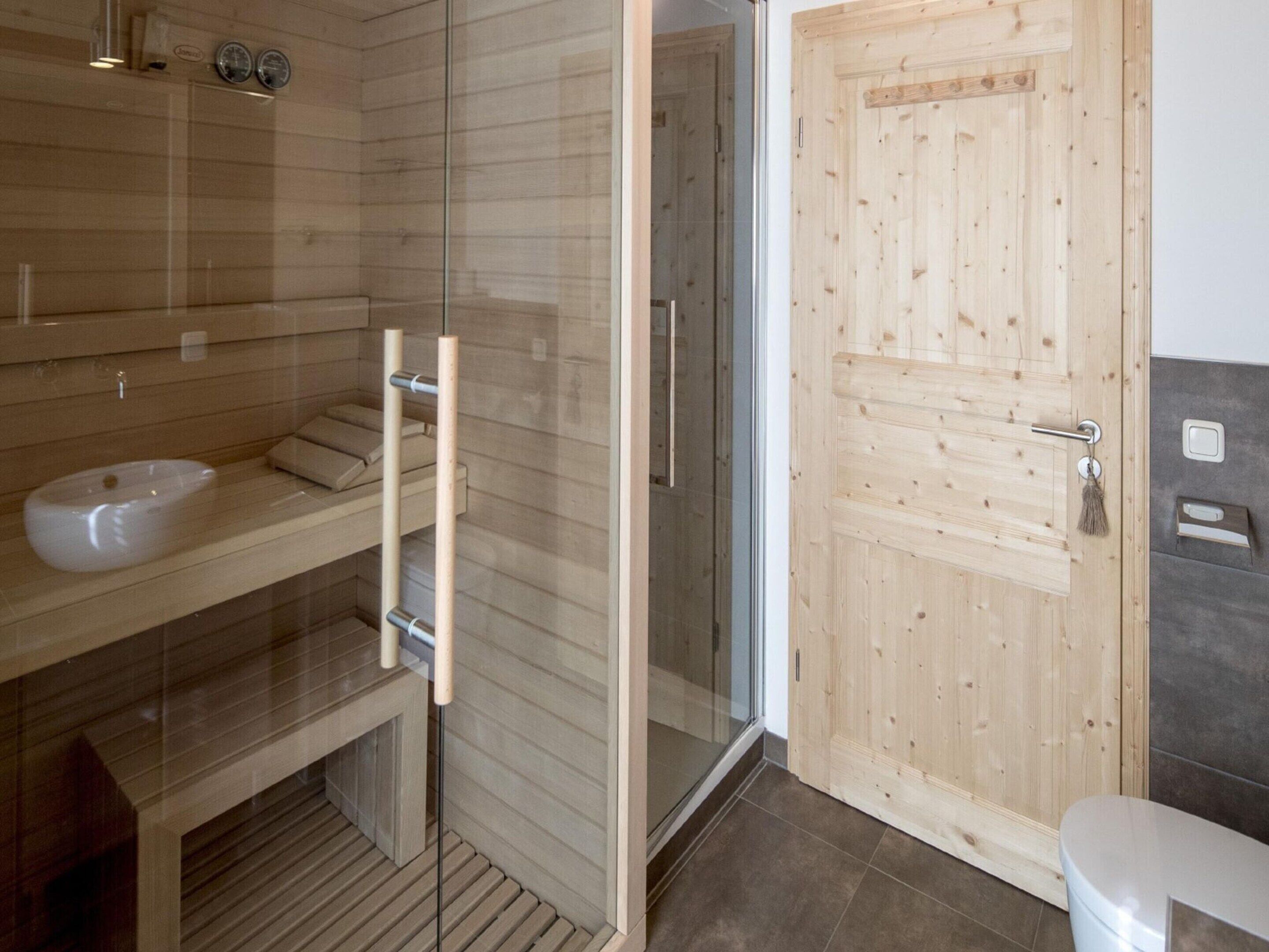 A modern bathroom with a glass-enclosed shower, a wooden vanity with a sink, and a toilet.