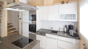 A modern kitchen with white cabinetry, a built-in oven, a stovetop, and a sink. - Luxurious Chalet in Sankt Georgen ob Murau with Hot Tub (Sankt Georgen am Kreischberg)