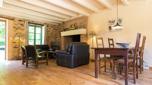 Ein gemütliches Wohnzimmer mit Kamin, Holzboden und einem Essbereich mit Tisch und Stühlen.