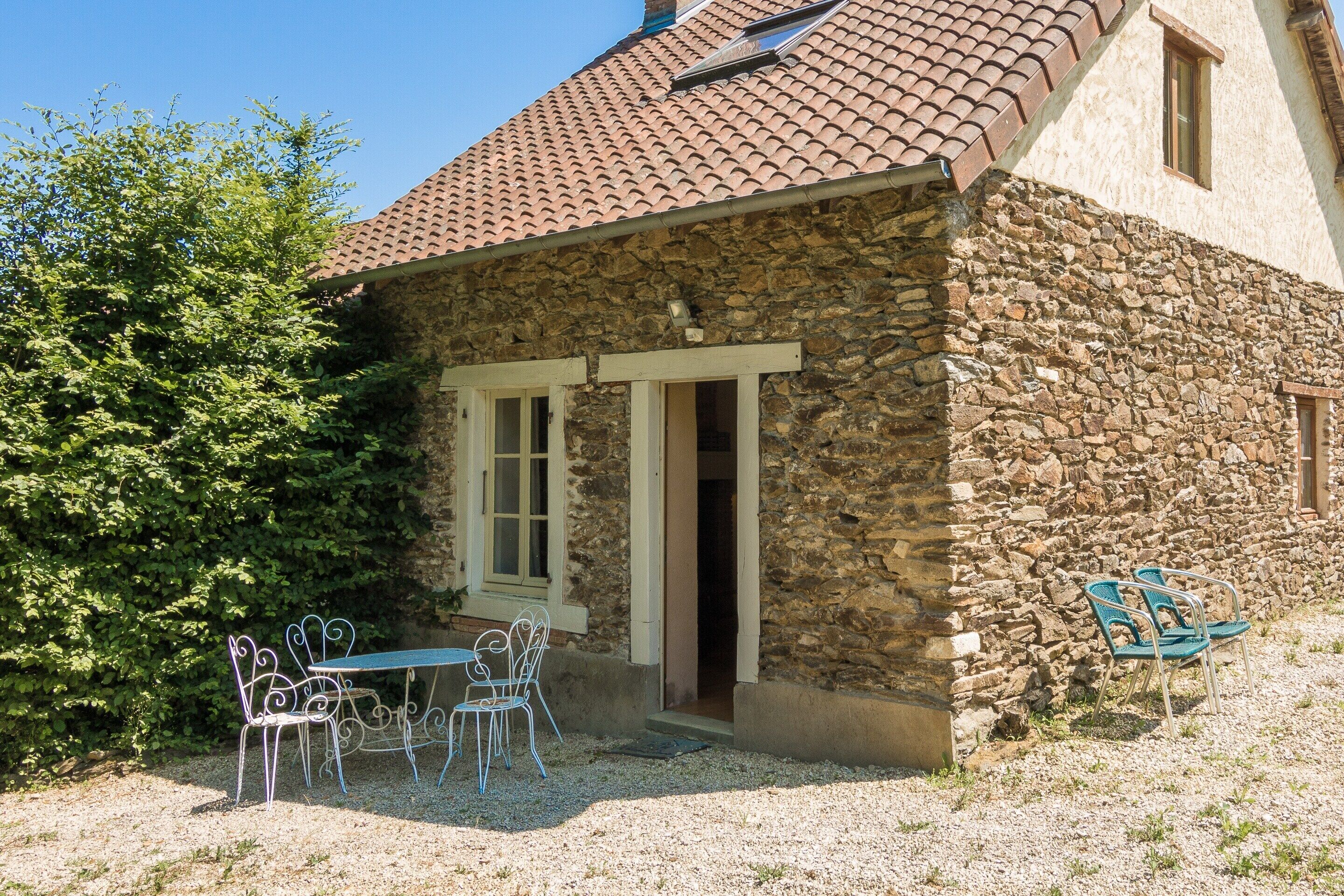 A stone building with a tiled roof, a door, and a window.