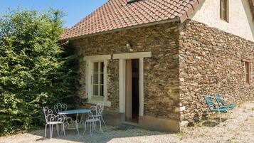A stone building with a tiled roof, a door, and a window.