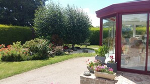 A garden with a gravel path, potted plants, and a conservatory with glass doors. - Peaceful Forest Stay in Pedernec (Pedernec)