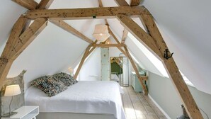 Une chambre mansardée chaleureuse, avec un lit, une table de chevet et une lampe.