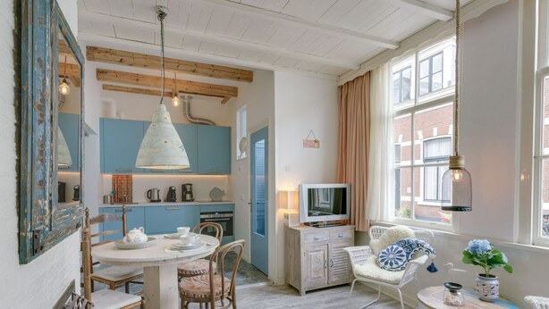 Une pièce confortable avec une table à manger, des chaises, un téléviseur et une fenêtre avec des rideaux.